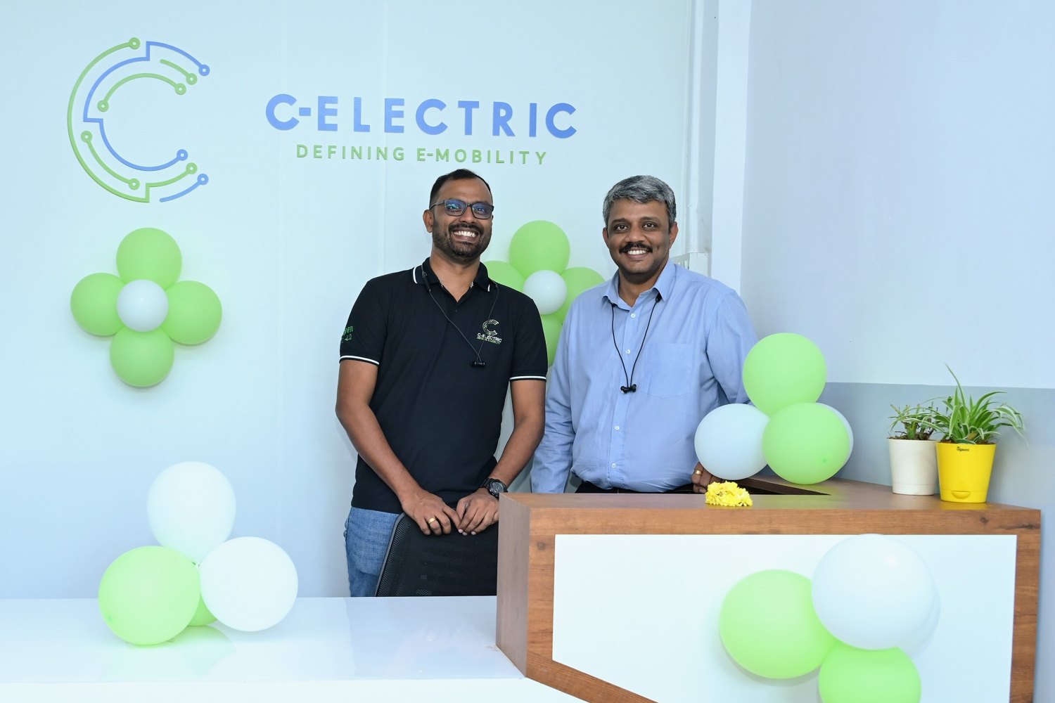 Co-founders Bavil Varghese and Ratheesh K. Nair in front of the C-Electric logo